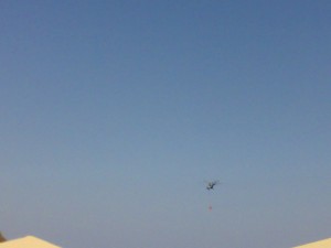 Вертолёт с пожарной ёмкостью  пролетает над отелем